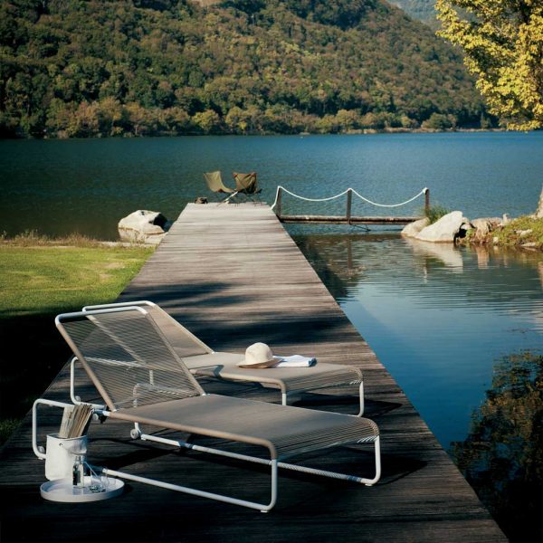 Image of pair of Harp modern white sun loungers with Sand colored rope seat and back, shown on boardwalk with lake and hills in background