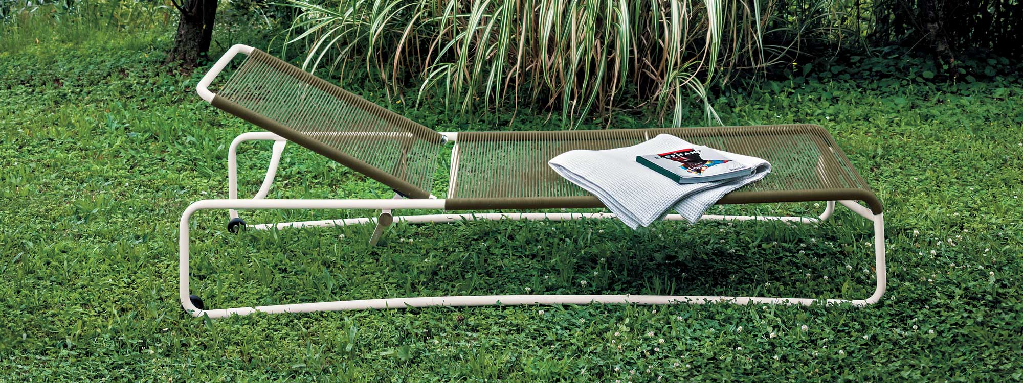 Image of Harp modern white sunbed with tobacco coloured rope seat and back, shown on grass