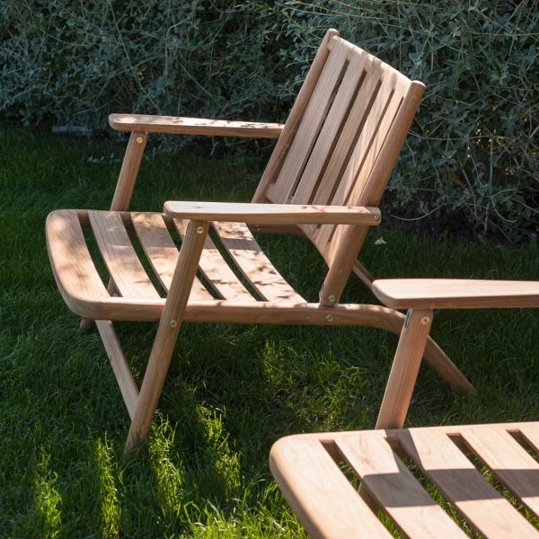 Image of pair of RODA Levante modern teak lounge chairs on grass, in light and shade of garden