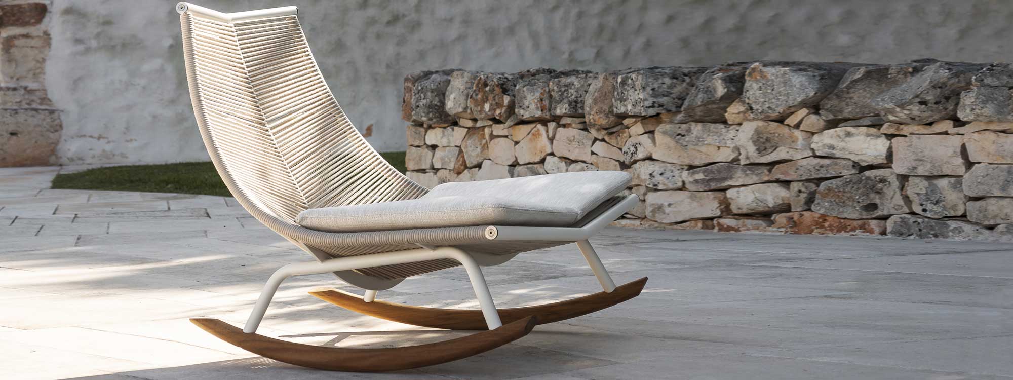 Image of RODA Laze outdoor rocking chair with Milk-Coloured frame and Sand cords, on terrace against drystone wall