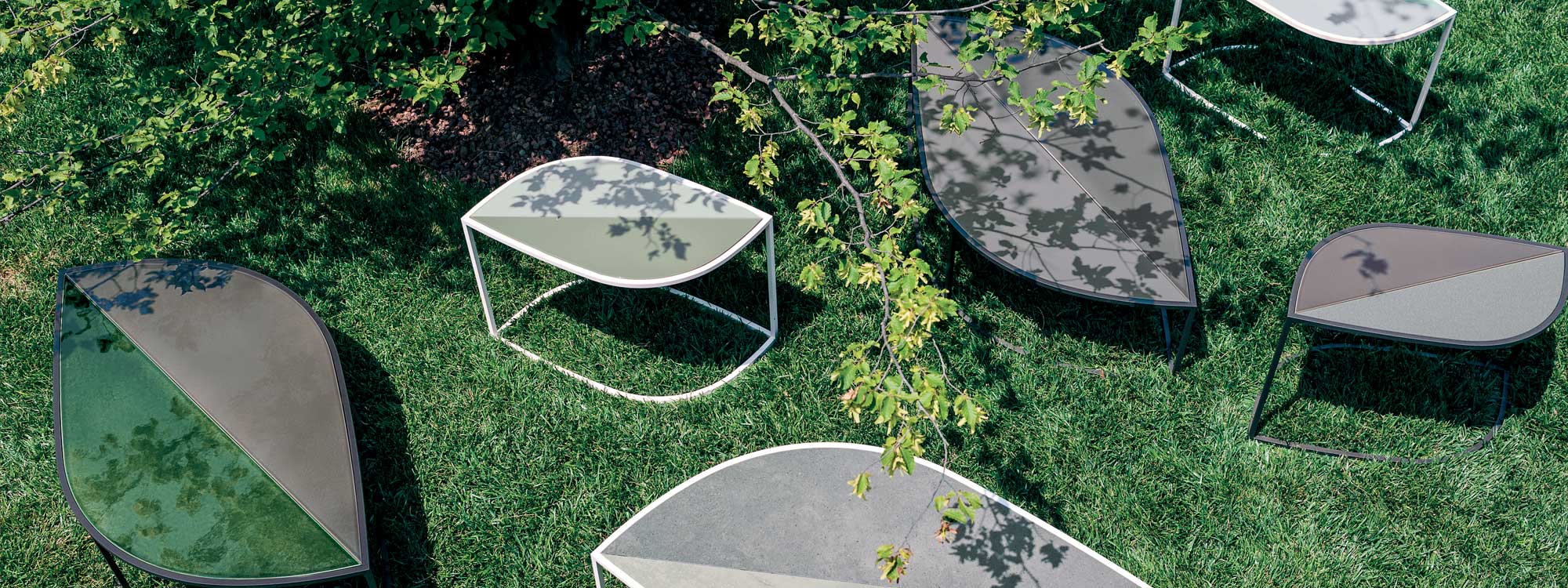 Collection of Leaf garden side tables shown on grassy lawn.