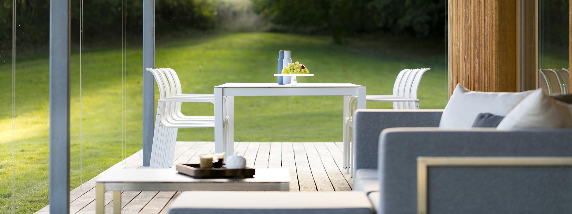 Image looking down wooden decked veranda with Lotus garden sofa and Puro outdoor dining furniture by Todus