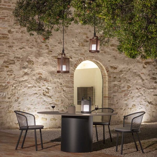 Nighttime shot of Branta garden table and Baza outdoo dining chairs beneath Luci LED garden lights in courtyard