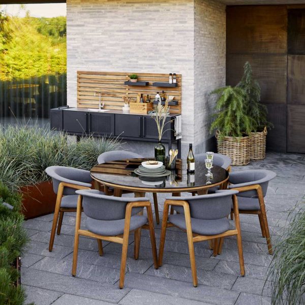 Image of Cane-line Luna modern garden chairs and Aspect circular dining table, with Drop outdoor kitchen in the background