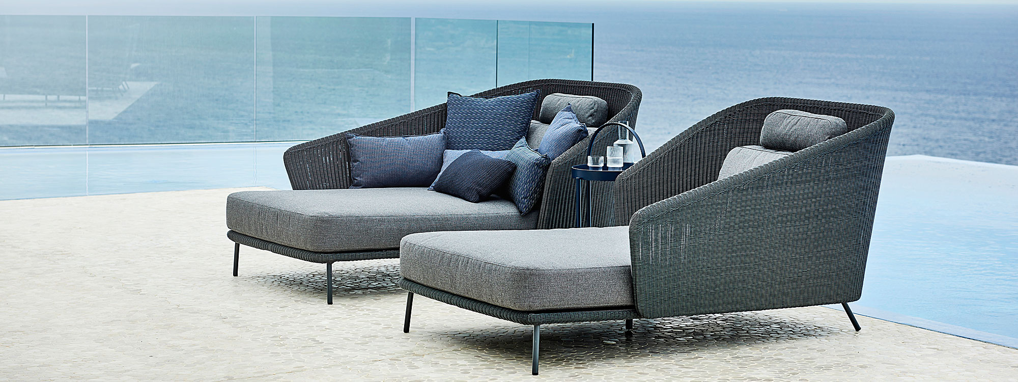 Image of pair of dark grey garden daybeds with grey cushions by Cane-line