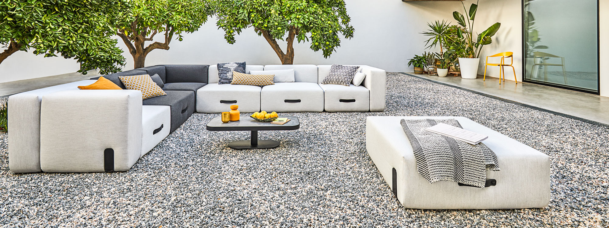 Grey & Anthracite Miami outdoor corner sofa on gravel courtyard beneath orange trees