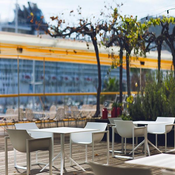 Image of white Wall Street chairs and Marisol square bistro tables by Vondom, shown on outdoor restaurant terrace