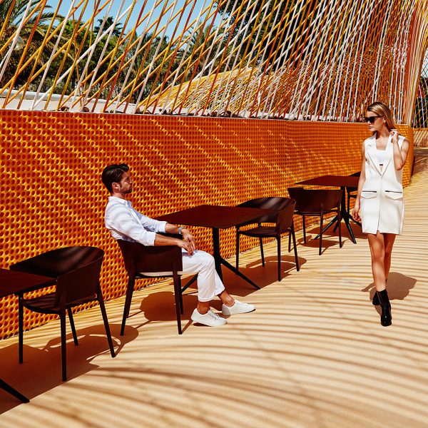 Image of Vondom black Africa chairs and black Mari-sol bistro tables beneath unusually large curved pergola structure