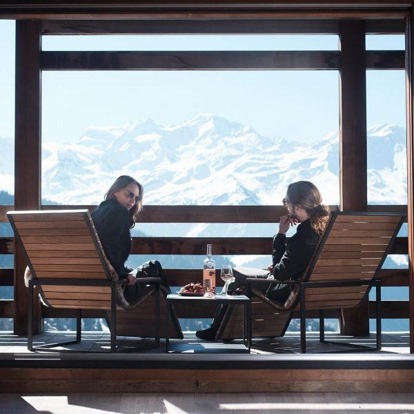 Couple sat in Roshults garden lounge chairs on terrace with spectacular Alpine view in background