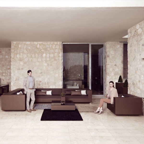 Image of couple sat around large brown Vela outdoor cover sofa beneath cantilevered terrace ceiling