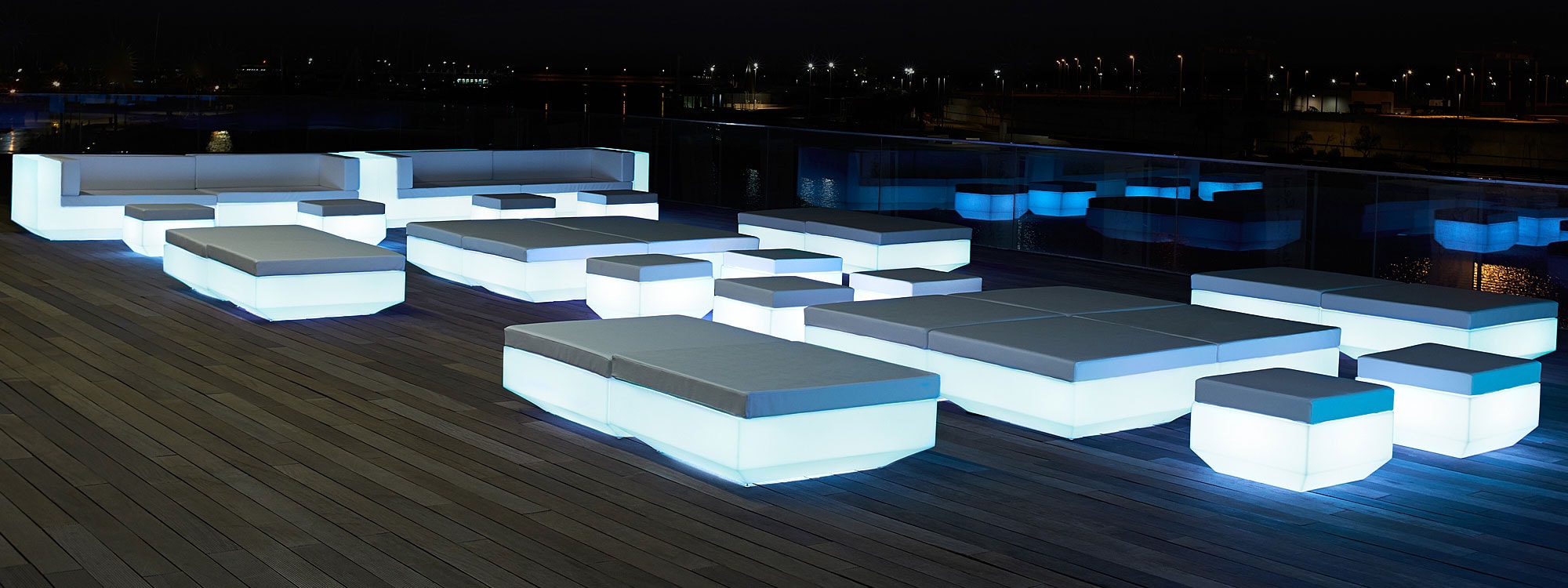 Nighttime image of illuminated Vondom Vela exterior lounge furniture and modular bar counter