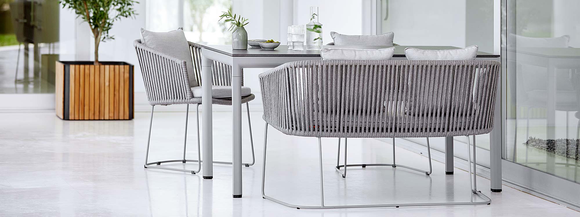 Image of light grey Drop garden dining table and light grey Soft Rope Moments dining chairs and dining bench by Cane-line