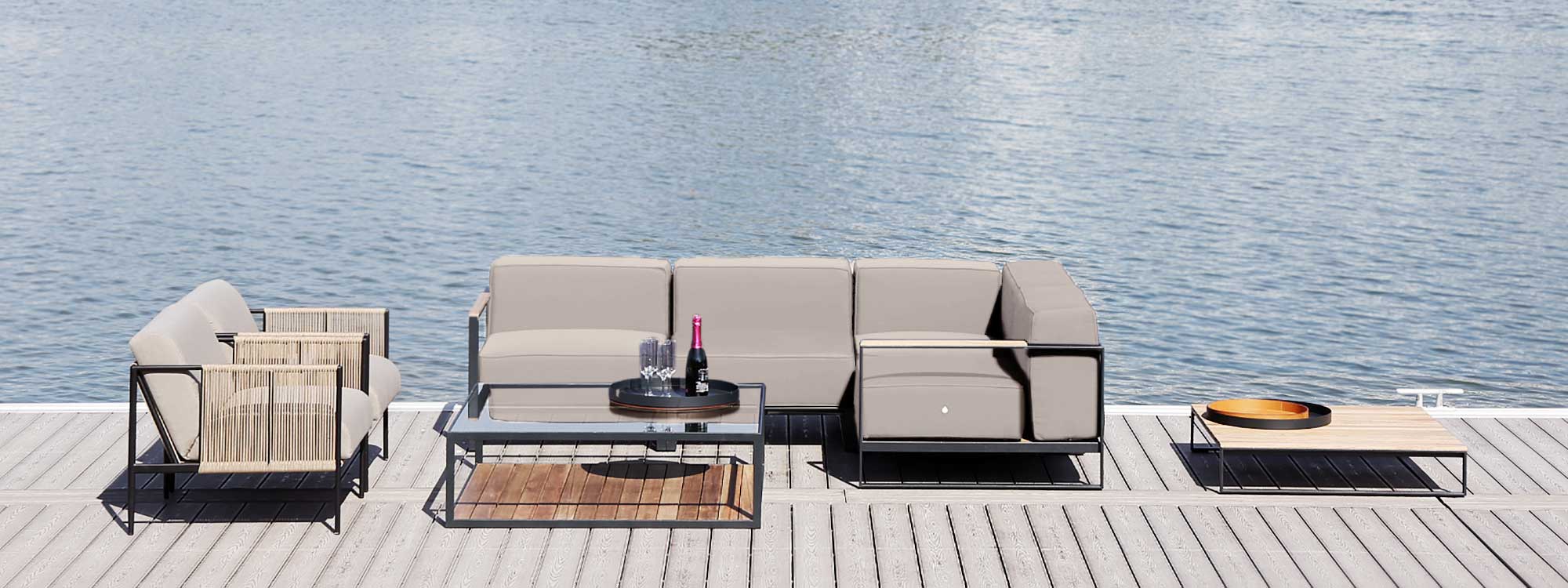 Image of Moore linear garden sofa and Antibes outdoor lounge chairs, shown on decked platform with still waters of a lake in the background