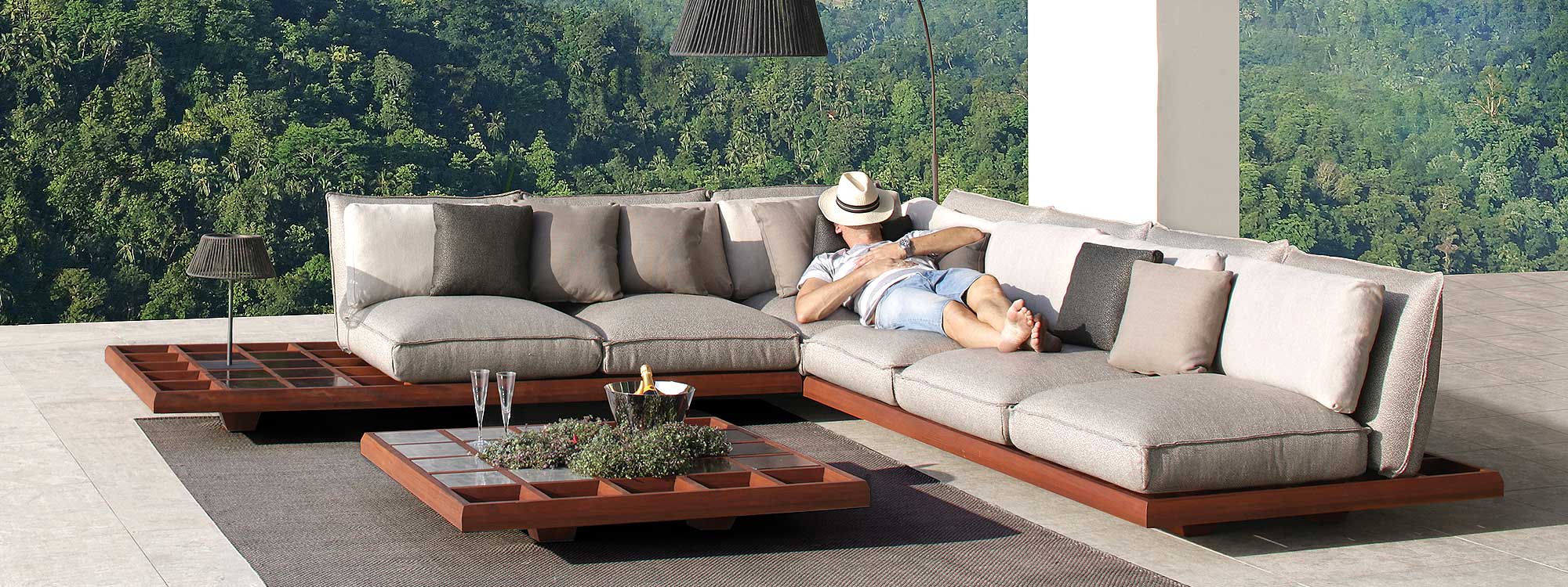 Image of man snoozing on Mozaix luxury outdoor sofa by Royal Botania, with lush woodland in background
