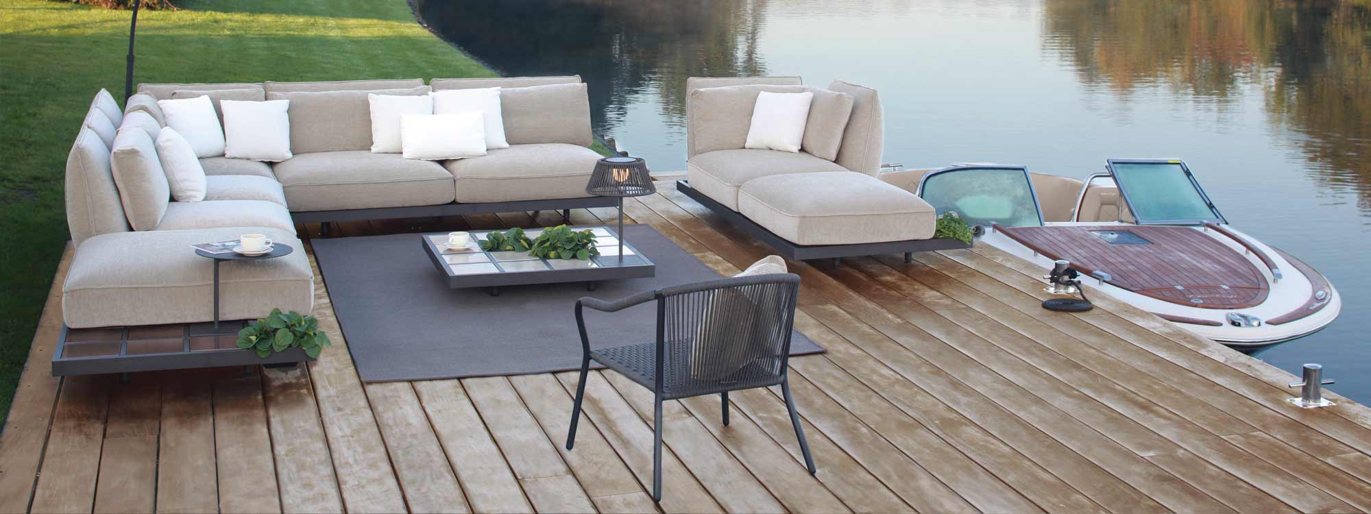 Image of lakeside installation of Royal Botania Mozaix Alu sofa with anthracite base and taupe cushions, with Riva speed boat moored alongside pontoon