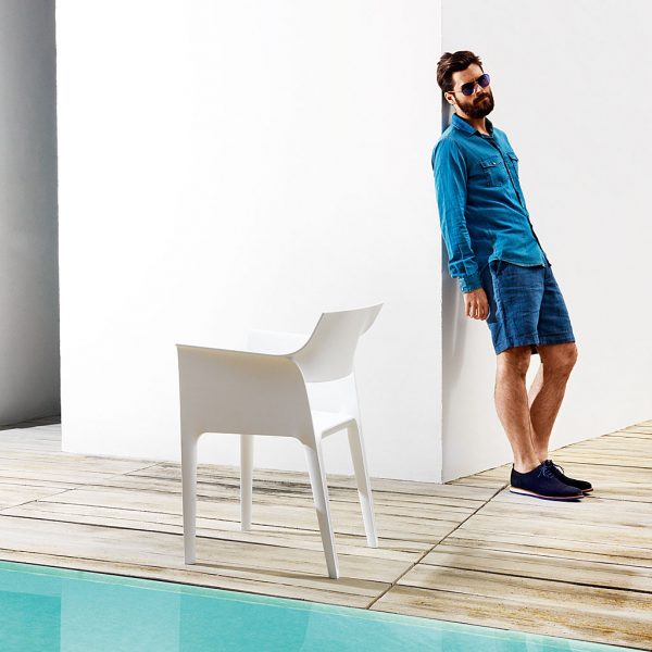 Image of hipster in sunglasses leaning against wall next to Vondom Pedrera white plastic bistro chair on poolside