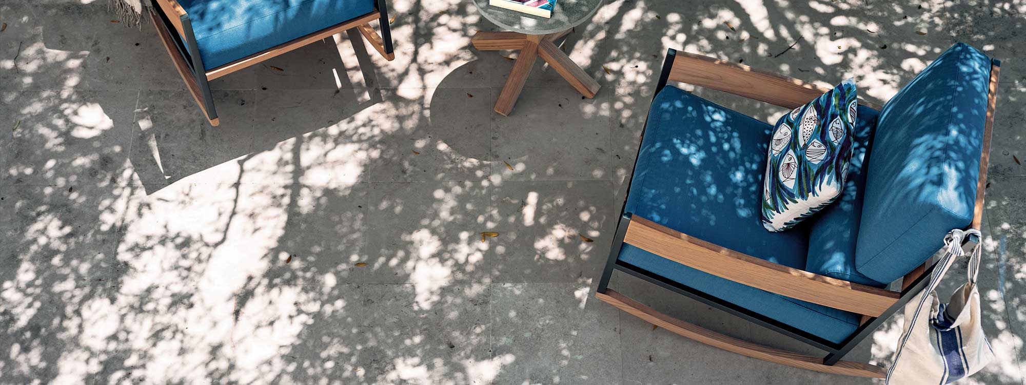Image of birdseye view of pair of Nap contemporary garden rocking chairs with blue cushions, next to Root exterior side table