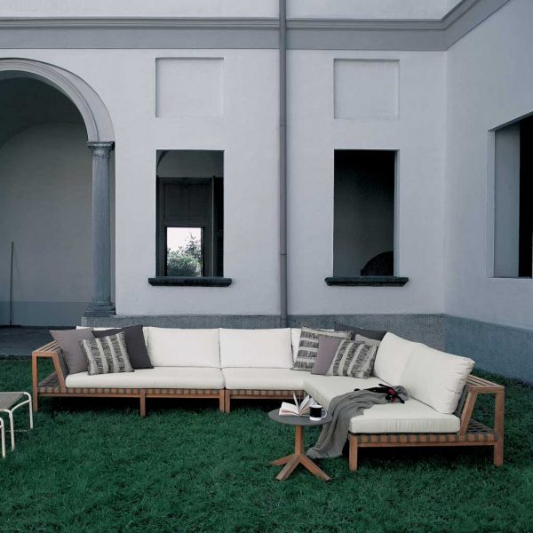 Network teak corner sofa with White cushions in grassy courtyard