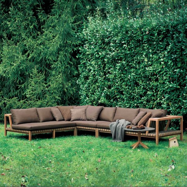 Image of RODA Network teak corner sofa with Tobacco webbing and Brown cushions on a verdant lawn with Root round side table