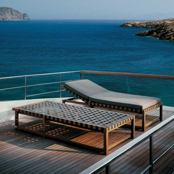 Image of pair of RODA Network minimalist sun loungers with webbed seat and back on deck of yacht with sea and headland in background