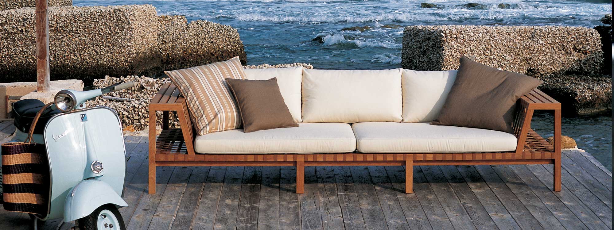 Network teak sofa with Tobacco webbing and White cushions with breaking waves in the background