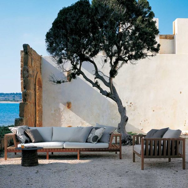 Image of RODA Network modern teak garden sofa and lounge chair with tree and white-washed wall in background