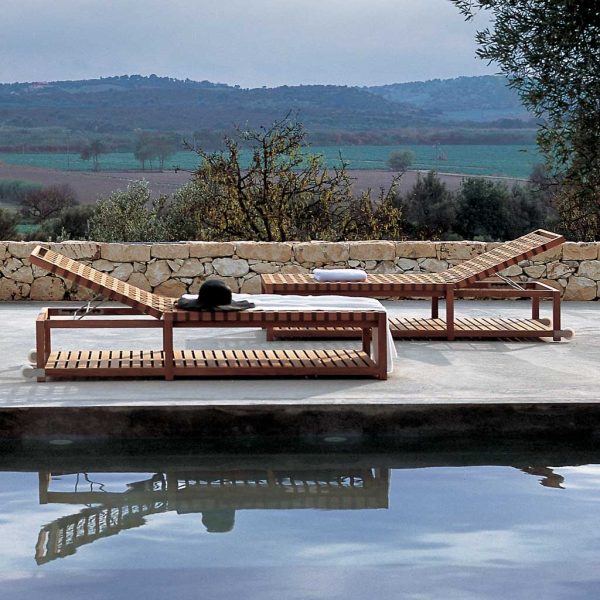 Network luxury teak sunbeds next to poolside with Italian countryside in background