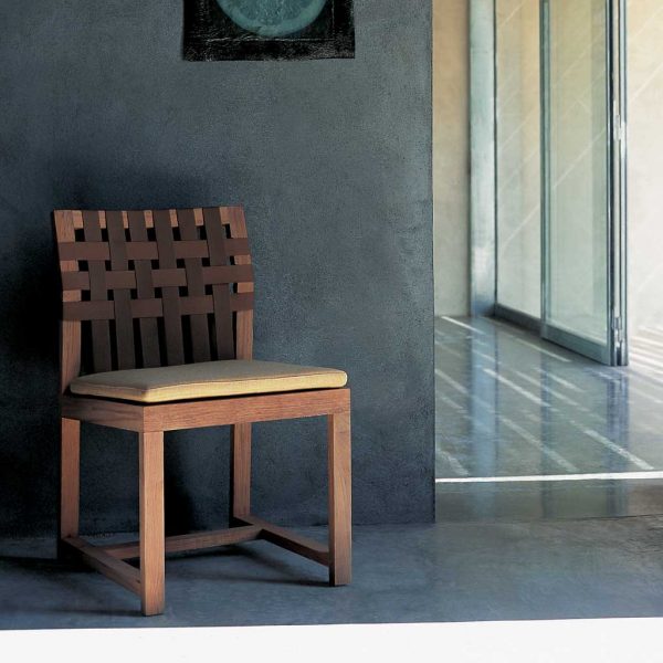 Interior shot of RODA Network teak garden chair with brown webbing and brown seat cushion pad, shown on poured concrete floor