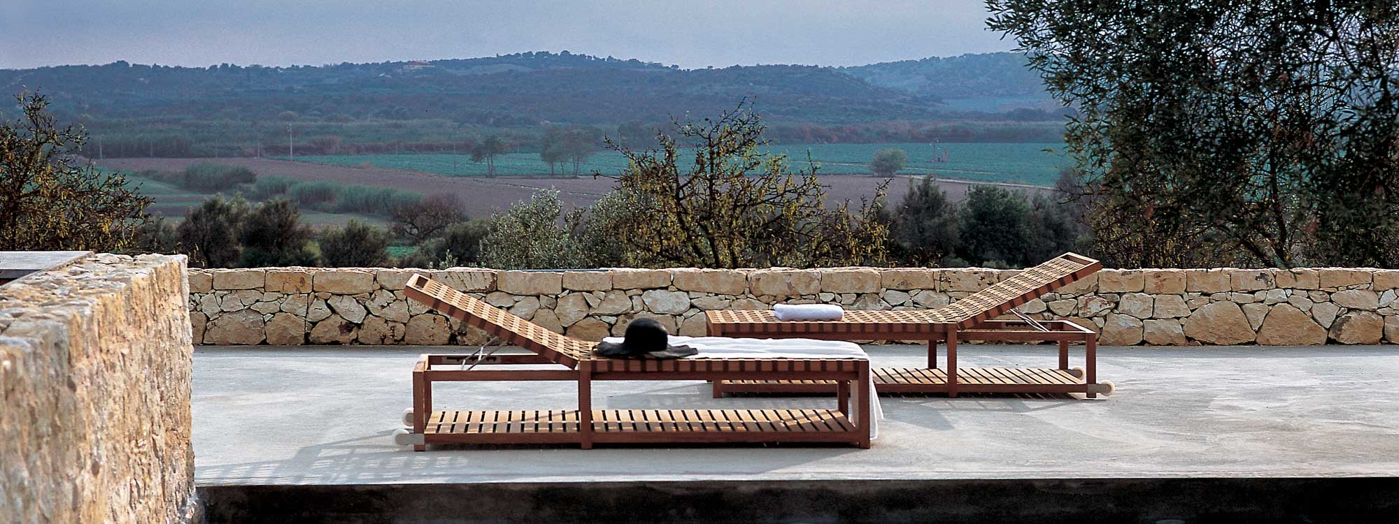 Pair of Network modern teak sunbeds on poolside with Italian countryside in background
