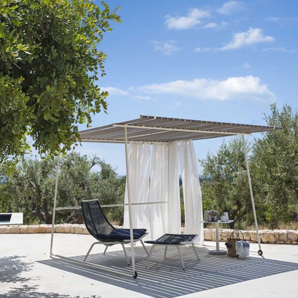 Image of RODA Ombrina pergola with wheels and Laze outdoor relax chair and foot stool on sunny rustic Italian terrace