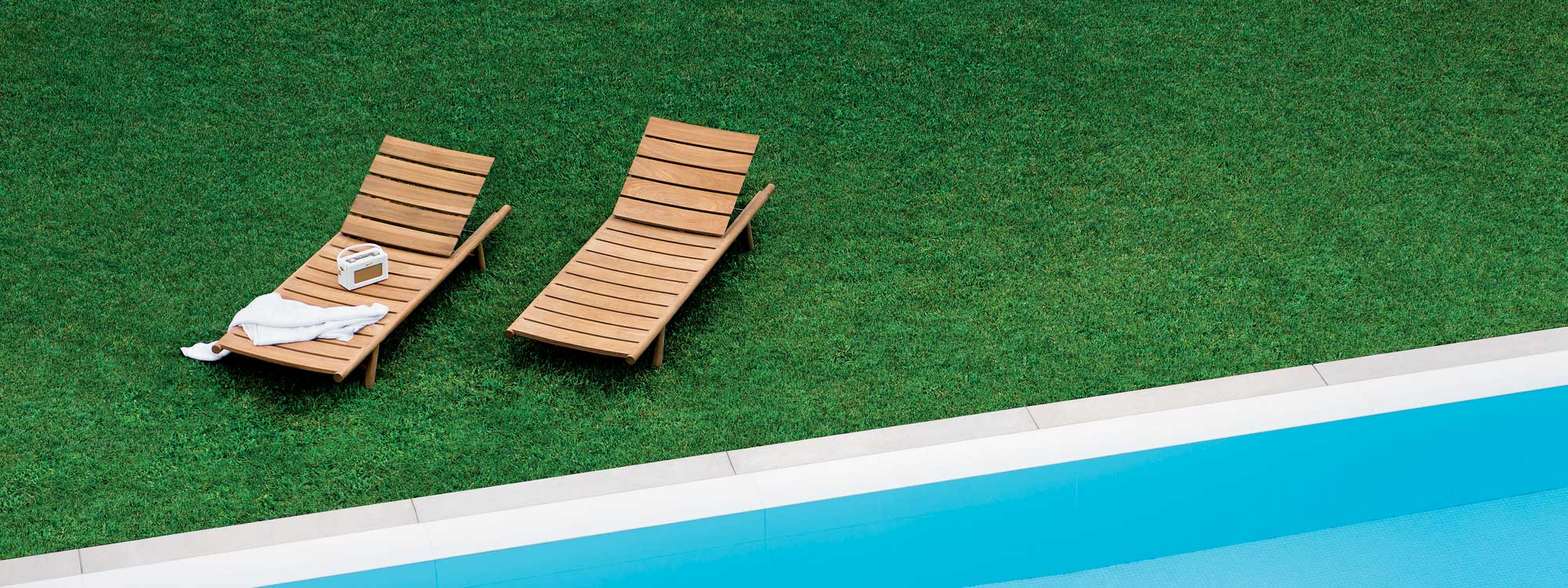 Image of aerial view of 2 RODA Orson teak sun loungers on green lawn next to swimming pool