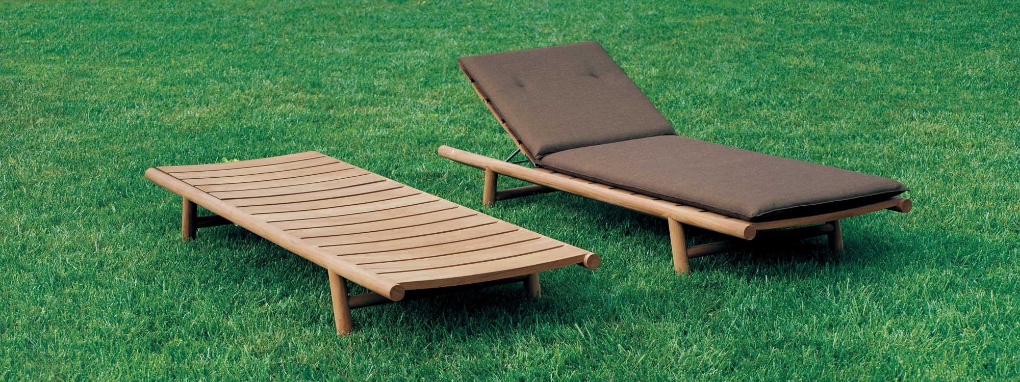 Orson teak sun beds with brown cushions on verdant lawn