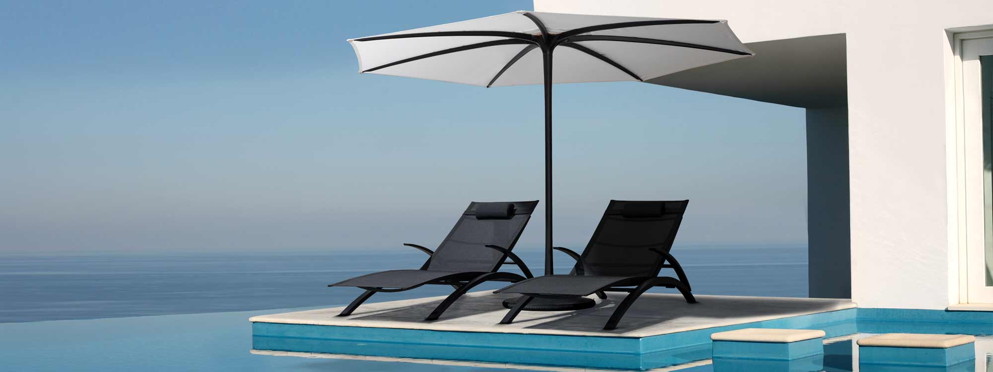 Royal Botania Palma parasol & black OZON loungers next to horizon swimming pool.