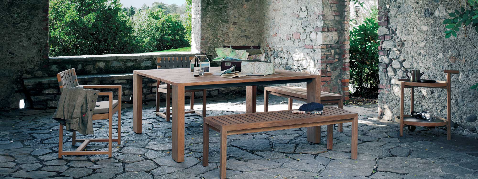 Pier teak table and bench with Network teak chairs in rustic Italian garden room.