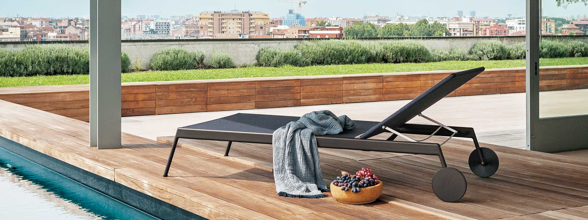 Piper modern sunbed with towel draped over it, with bowl of juicy grapes next to it.