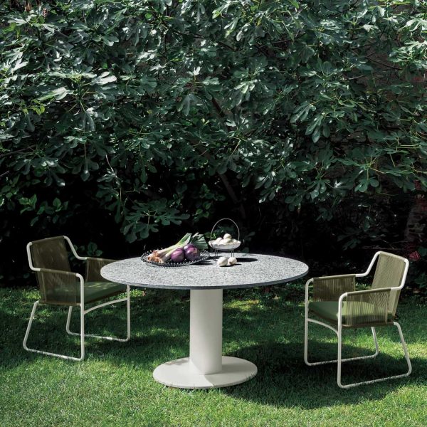Image of RODA Platter round garden dining table with Harp modern outdoor chairs on lawn with trees in the background
