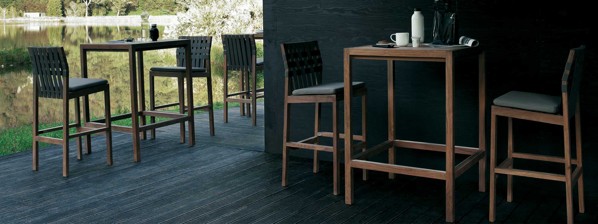 Image of lakeside terrace with Plaza teak bar tables and Network modern teak bar stools by RODA