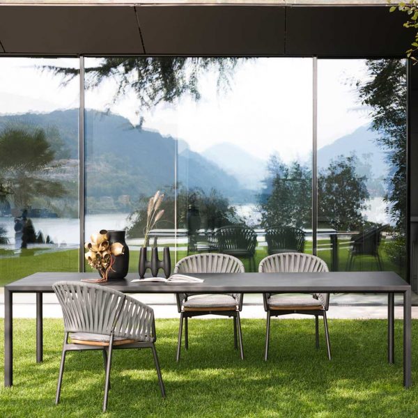 Image of RODA Plein Air rectangular garden table and Piper chairs on terrace, with reflection of hills and lake on windows in background