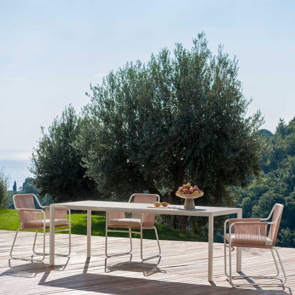 Image of RODA Plein Air white garden table and Harp white outdoor chairs on sunny terrace, with olive tree in background