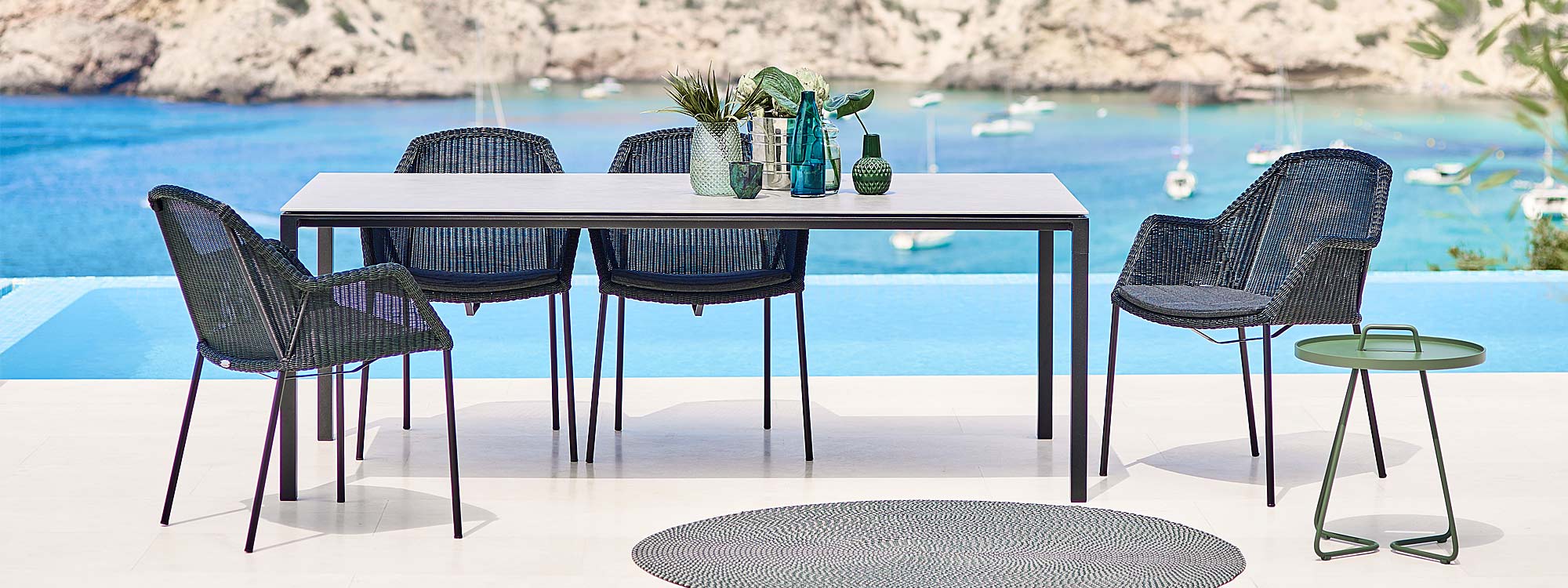 Image of black Breeze chairs and Pure garden dining table by Caneline, with bay and yachts in the background