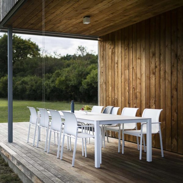 Image of Puro white garden dining set by Todus on wooden decking beneath cantilevered ceiling