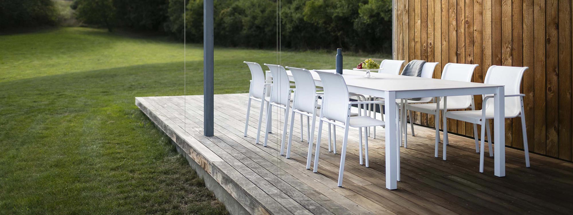 Image of Puro large white garden table and Puro white carver chairs on wooden decked veranda