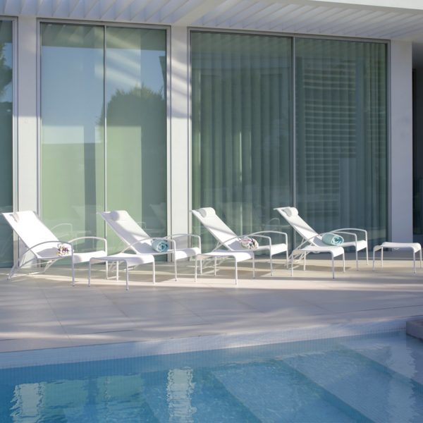 Image of row of white QT 195 reclining garden chairs and foot stools by Royal Botania along poolside