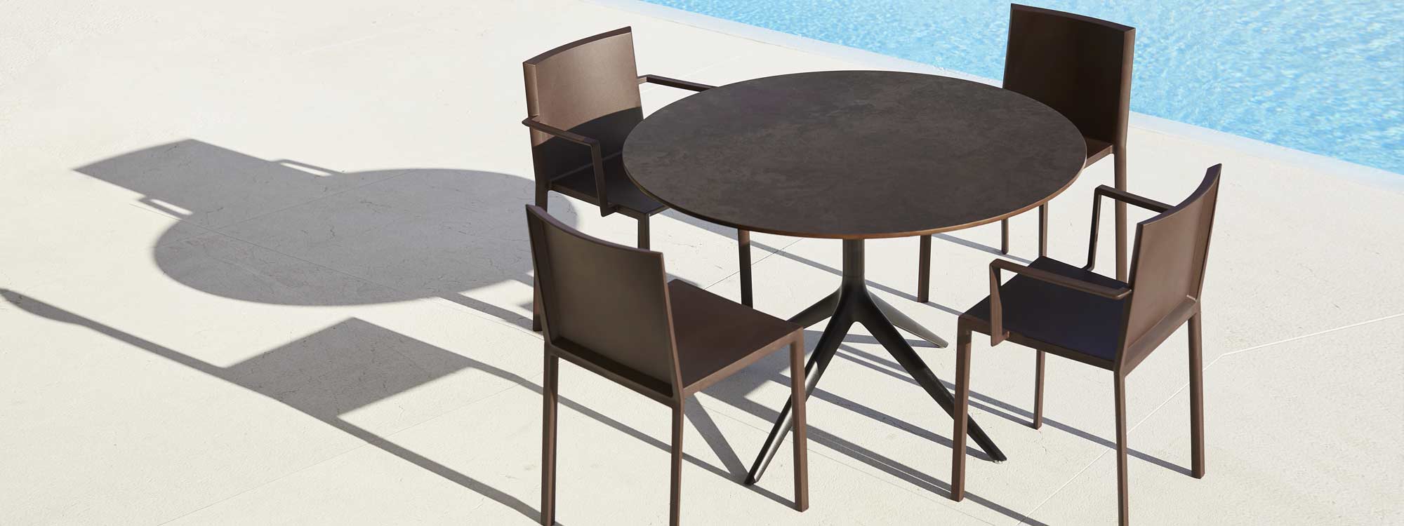 Image of Quartz brown garden chairs around Vondom circular table on sunny poolside