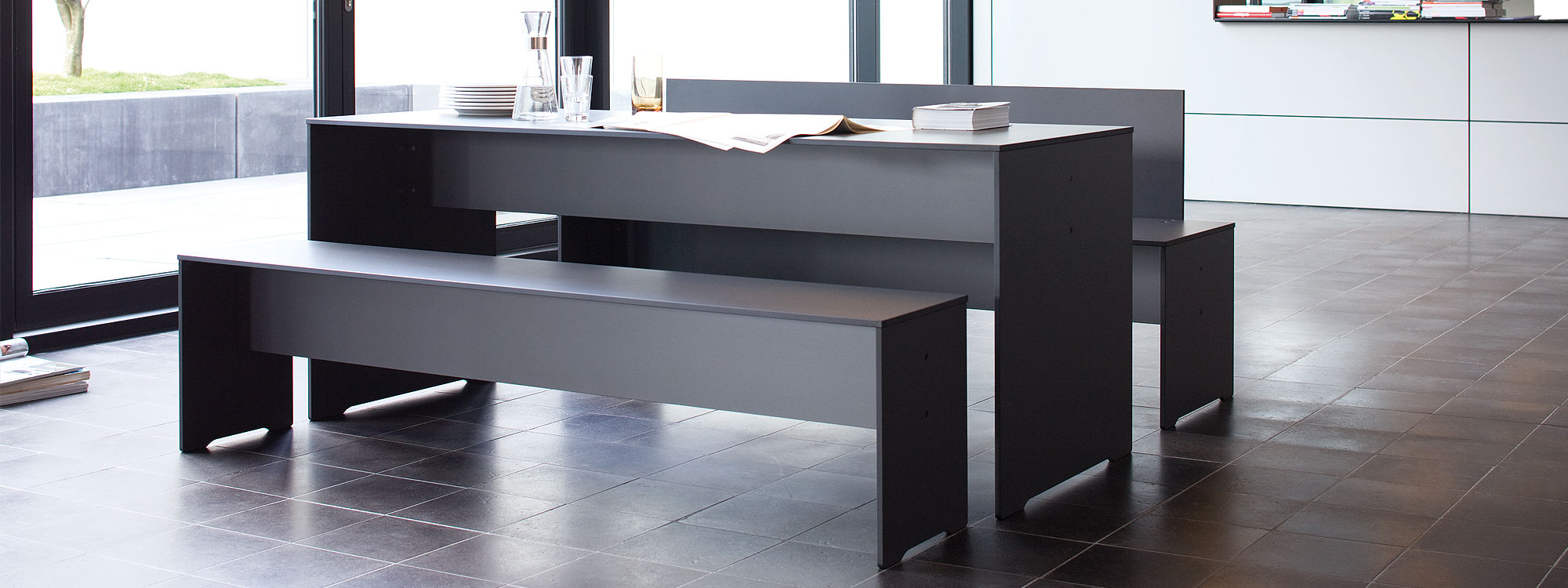 Image of dark grey RIVA table and bench set by Conmoto which can be used anywhere in the garden or inside the home