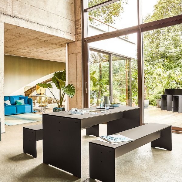 Image of RIVA dark grey dining table and bench seats in minimalist concrete house with large windows