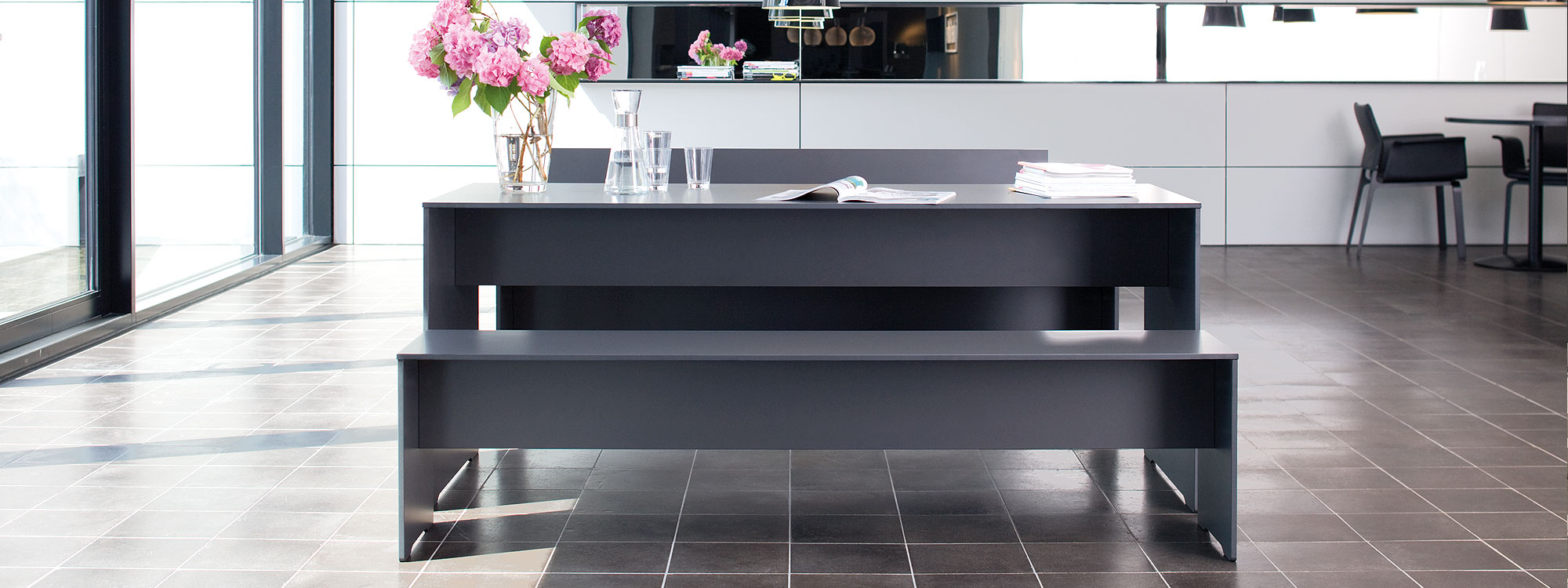 Image of RIVA dark grey table and benches by Conmoto, shown within minimalist house interior