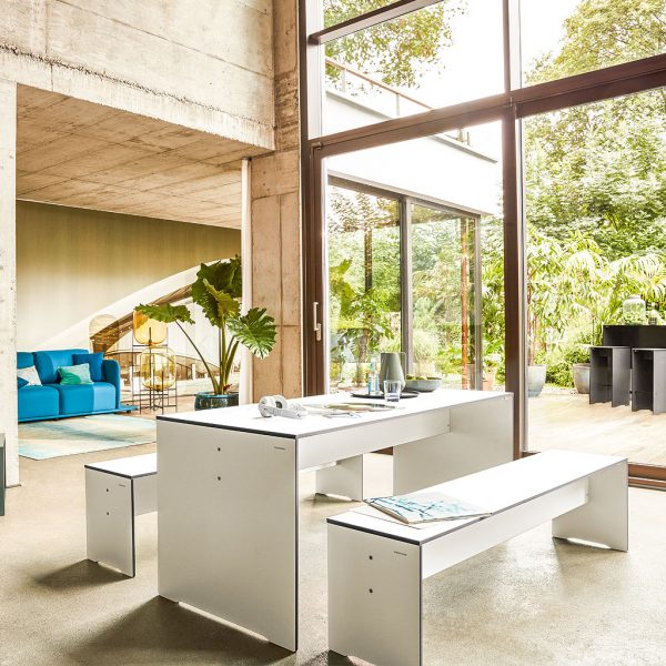 Image of RIVA white dining table and bench seats within modern concrete home with large windows