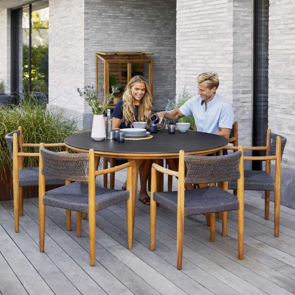 Image of couple enjoying breakfast whilst sat on Royal Teak garden chairs around Apsect round teak table by Cane-line