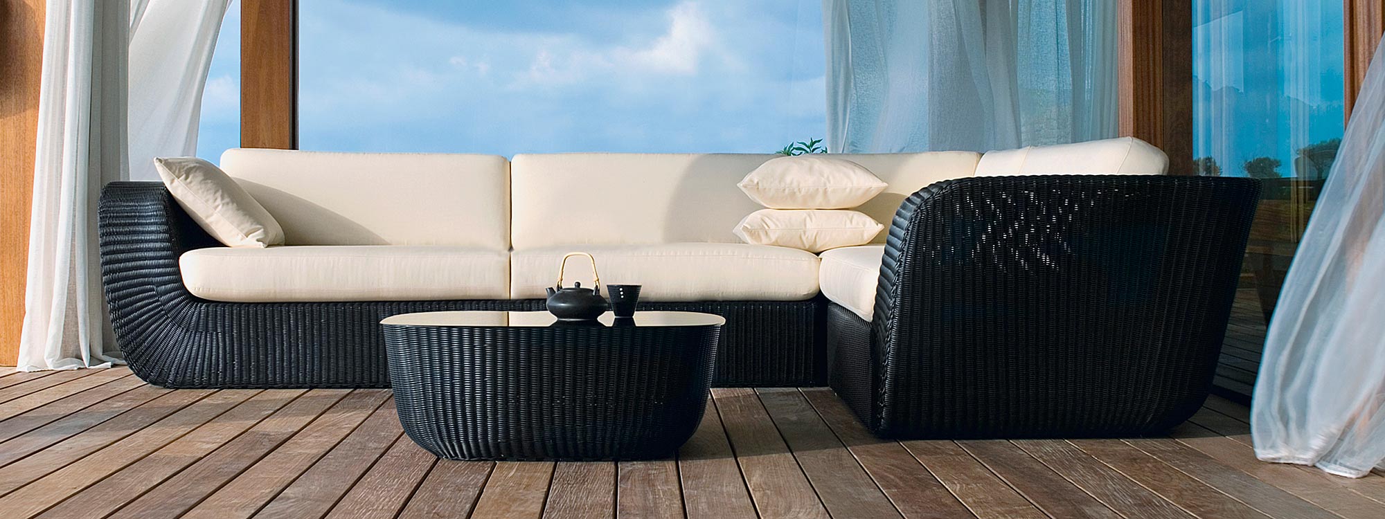 Image of black Savannah woven garden corner sofa with white cushions by Cane-line